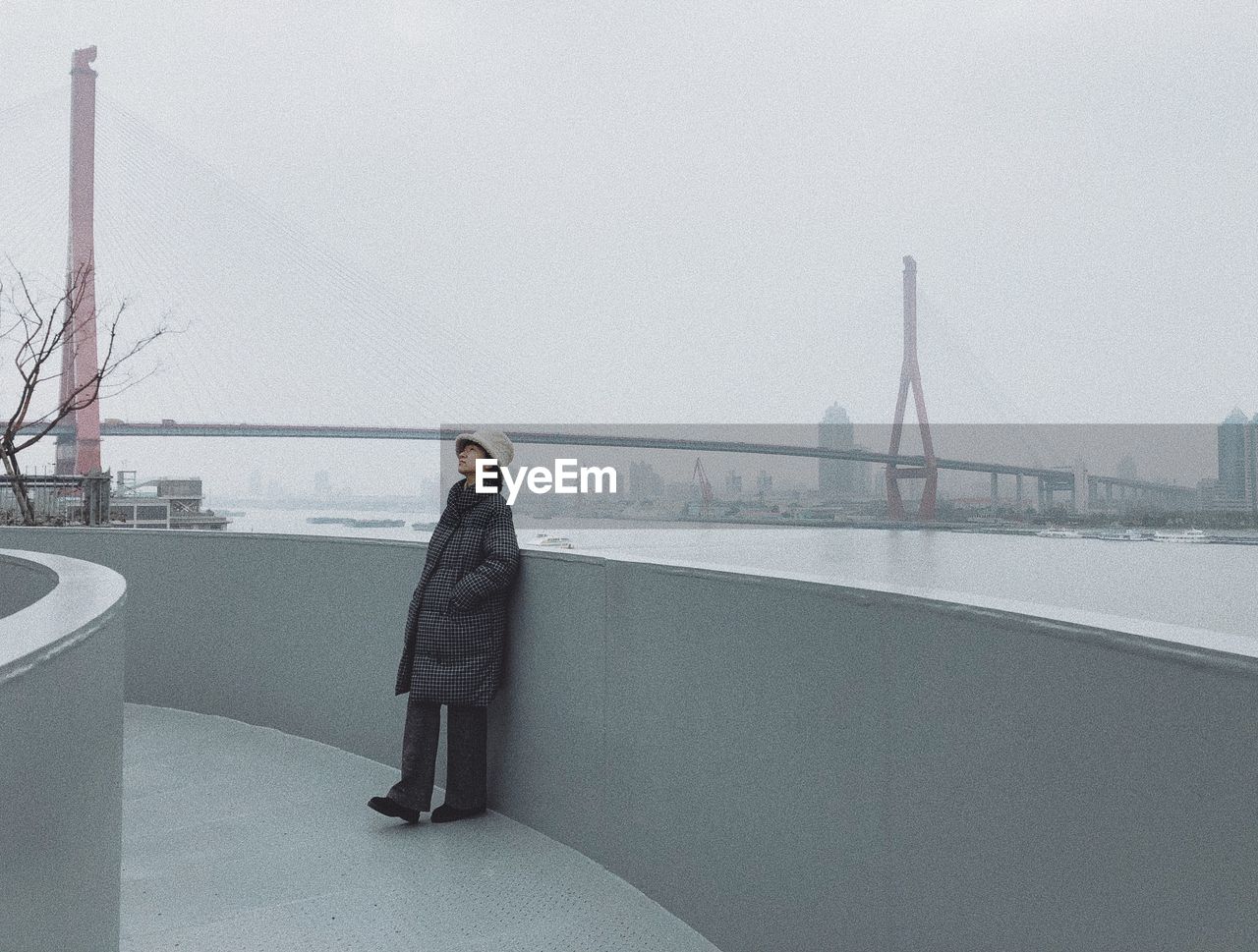 Side view of woman standing on bridge against sky