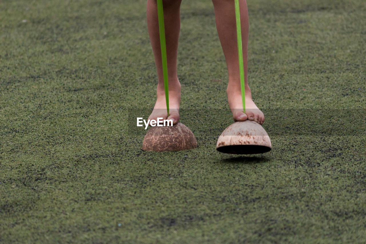 Low section of child walking on coconut shells at field