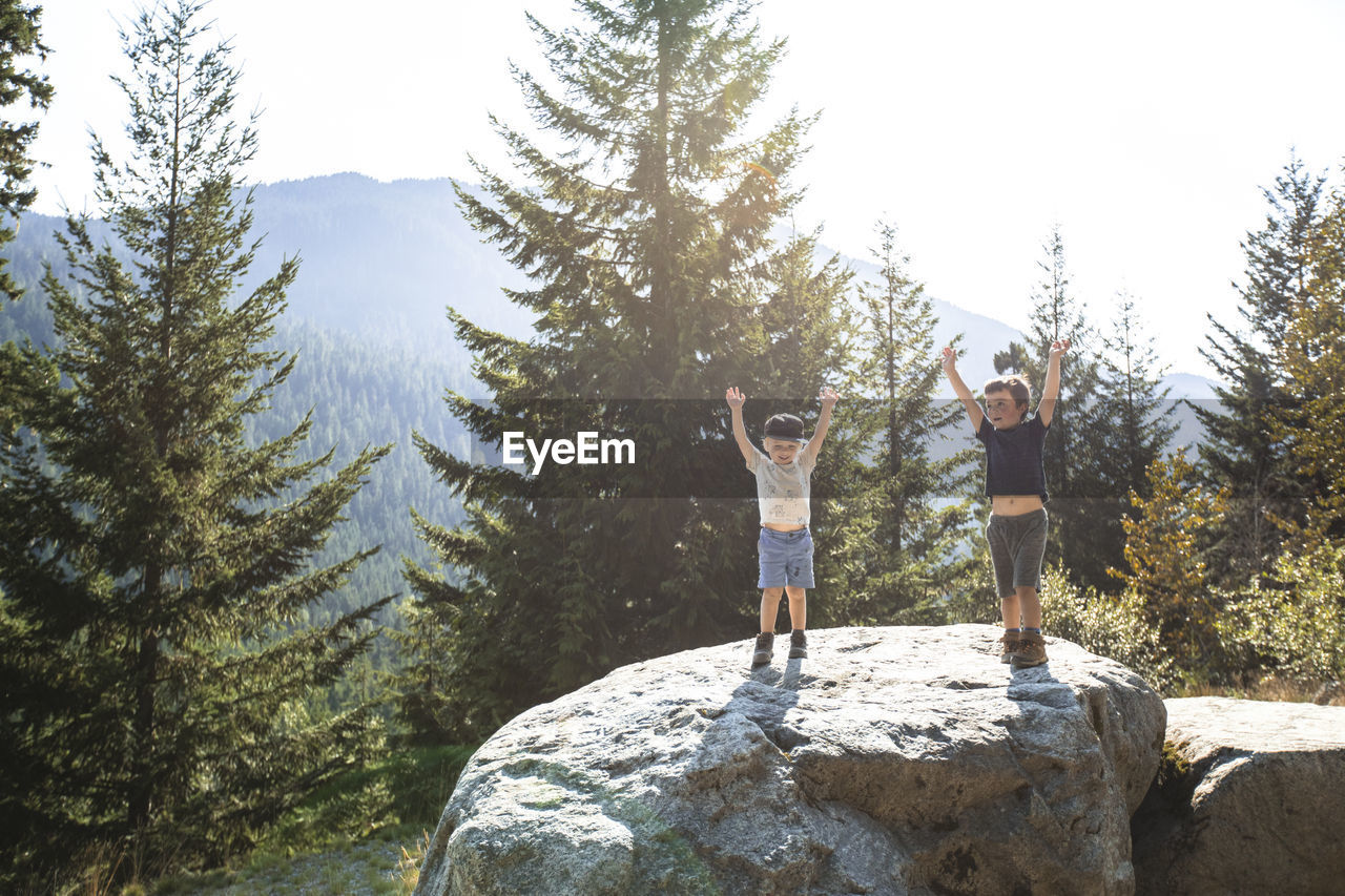 Two young hikers raise their hands in celebration, completing hike.