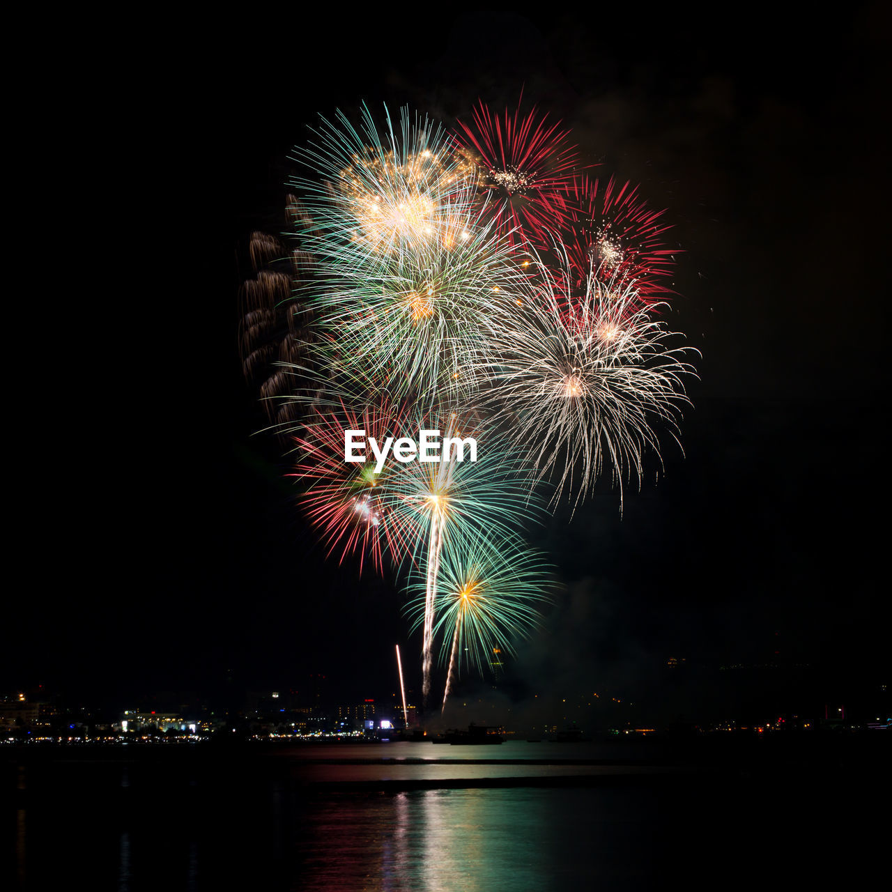 Firework display in city against sky at night