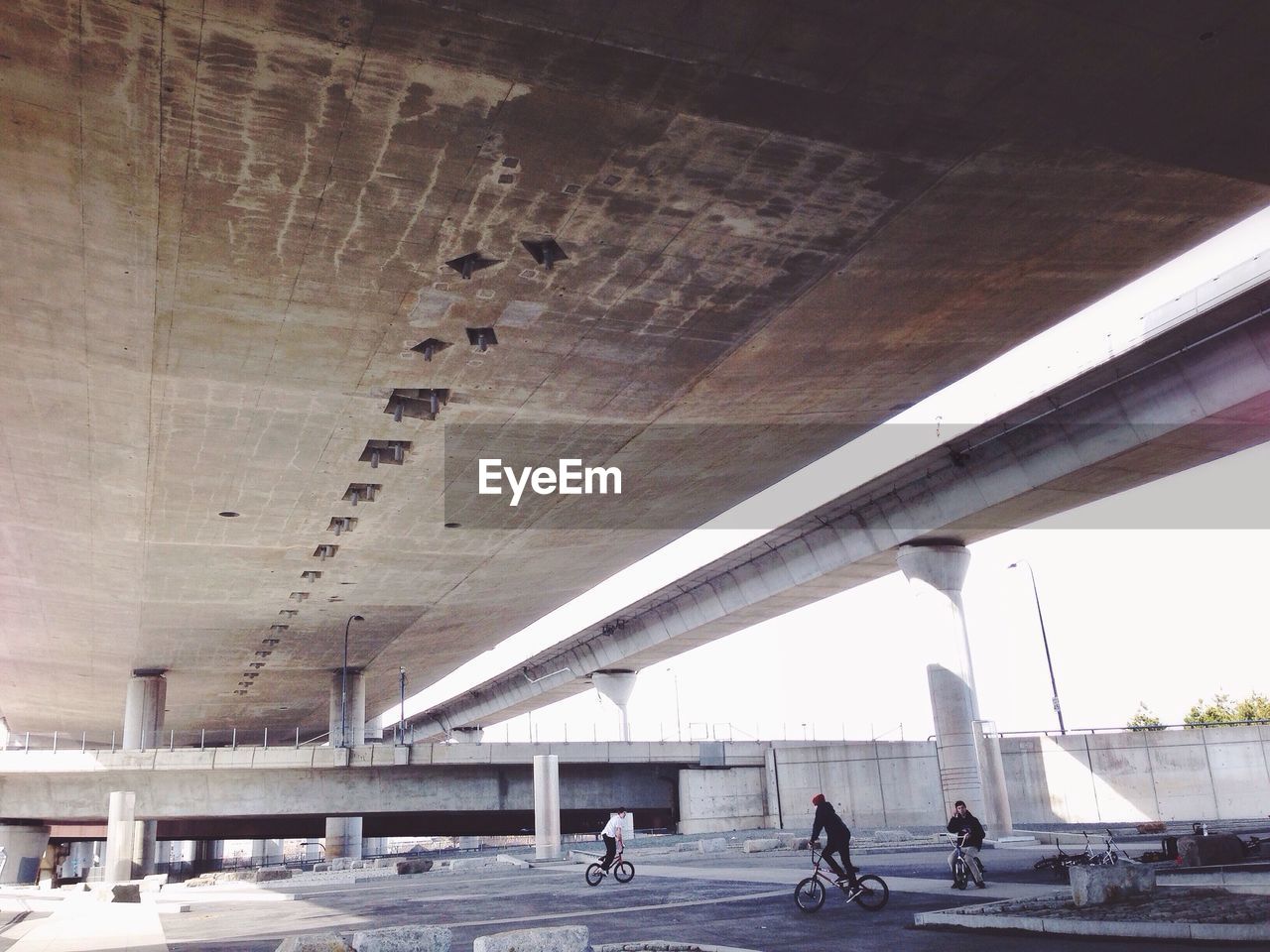 Boys cycling under bridge