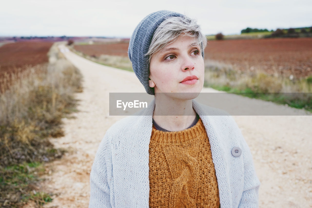 Close-up of woman wearing knit hat while standing on dirt road