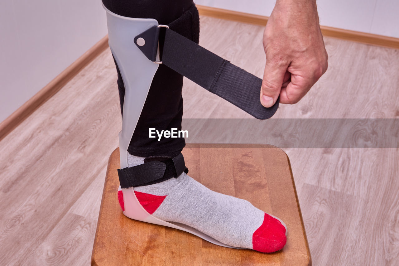 low section of man tying shoelace on floor