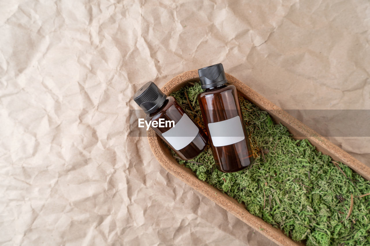 Dropper bottles of serum or oil with vitamin c with blank labels lying on a moss