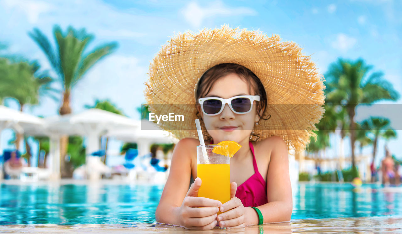 Portrait of girl with orange glass at poolside