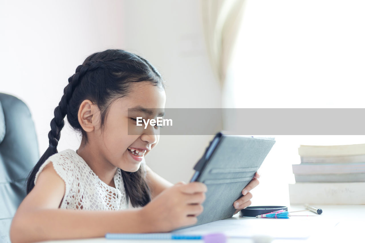 Smiling girl using digital tablet at table