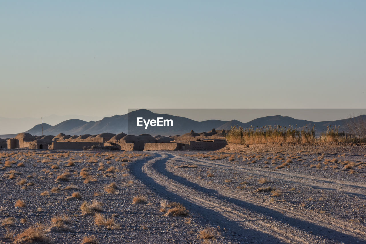 Scenic view of field against clear sky road directing inside the village