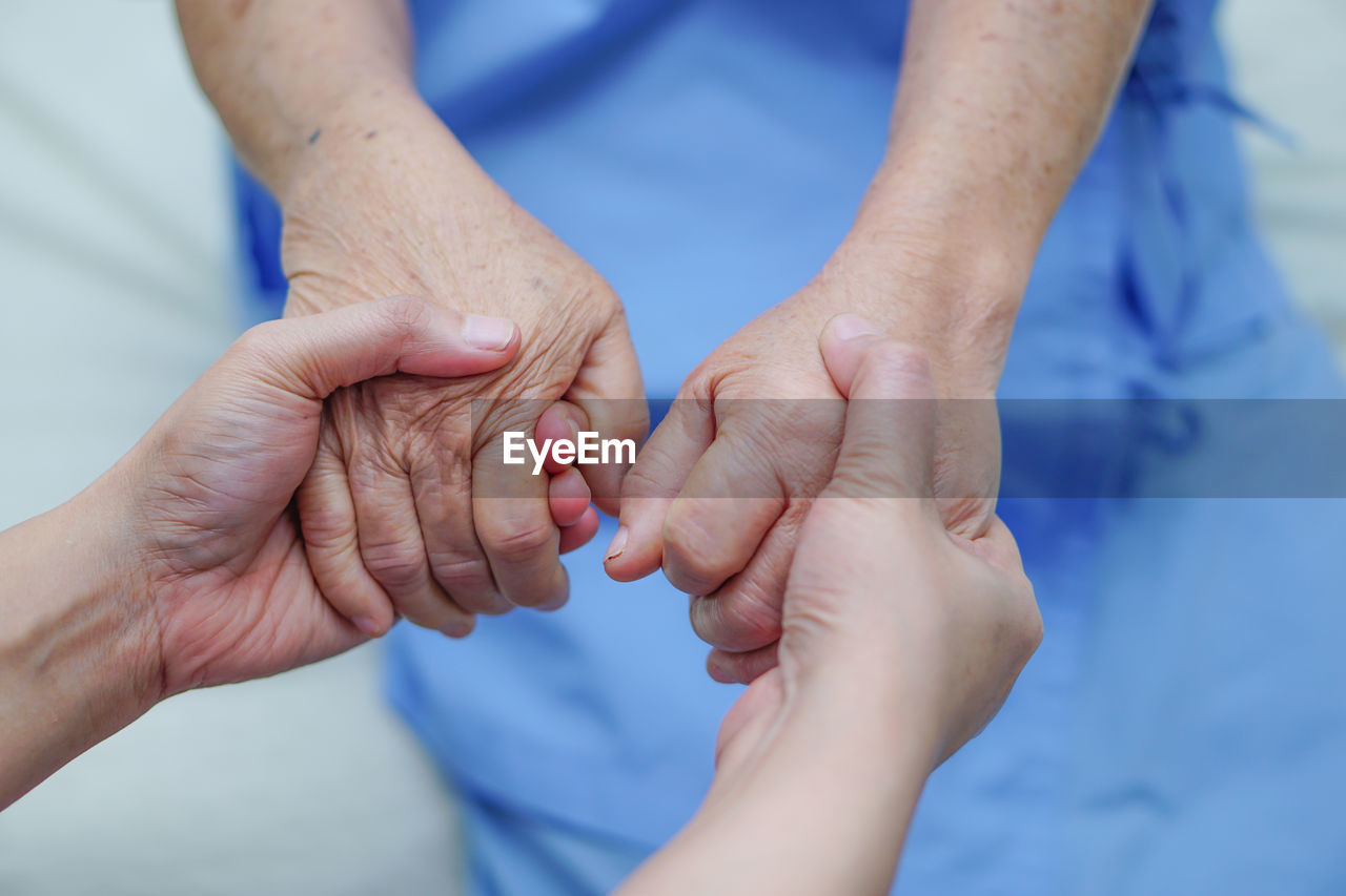 Cropped image of doctor holding hands with female patient in hospital