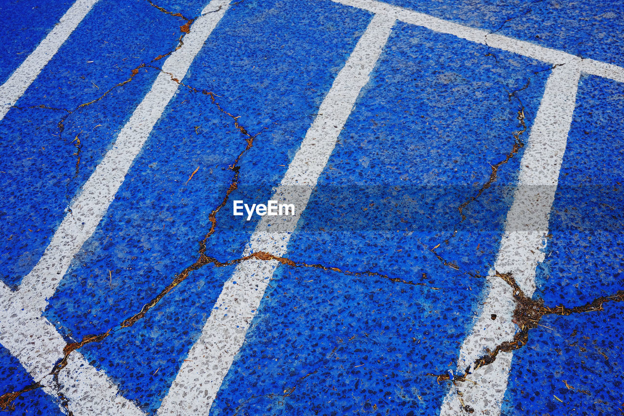 blue, high angle view, asphalt, day, full frame, flooring, no people, line, road, road surface, backgrounds, marking, pattern, road marking, symbol, white, sign, textured, lane, outdoors, transportation, floor, city