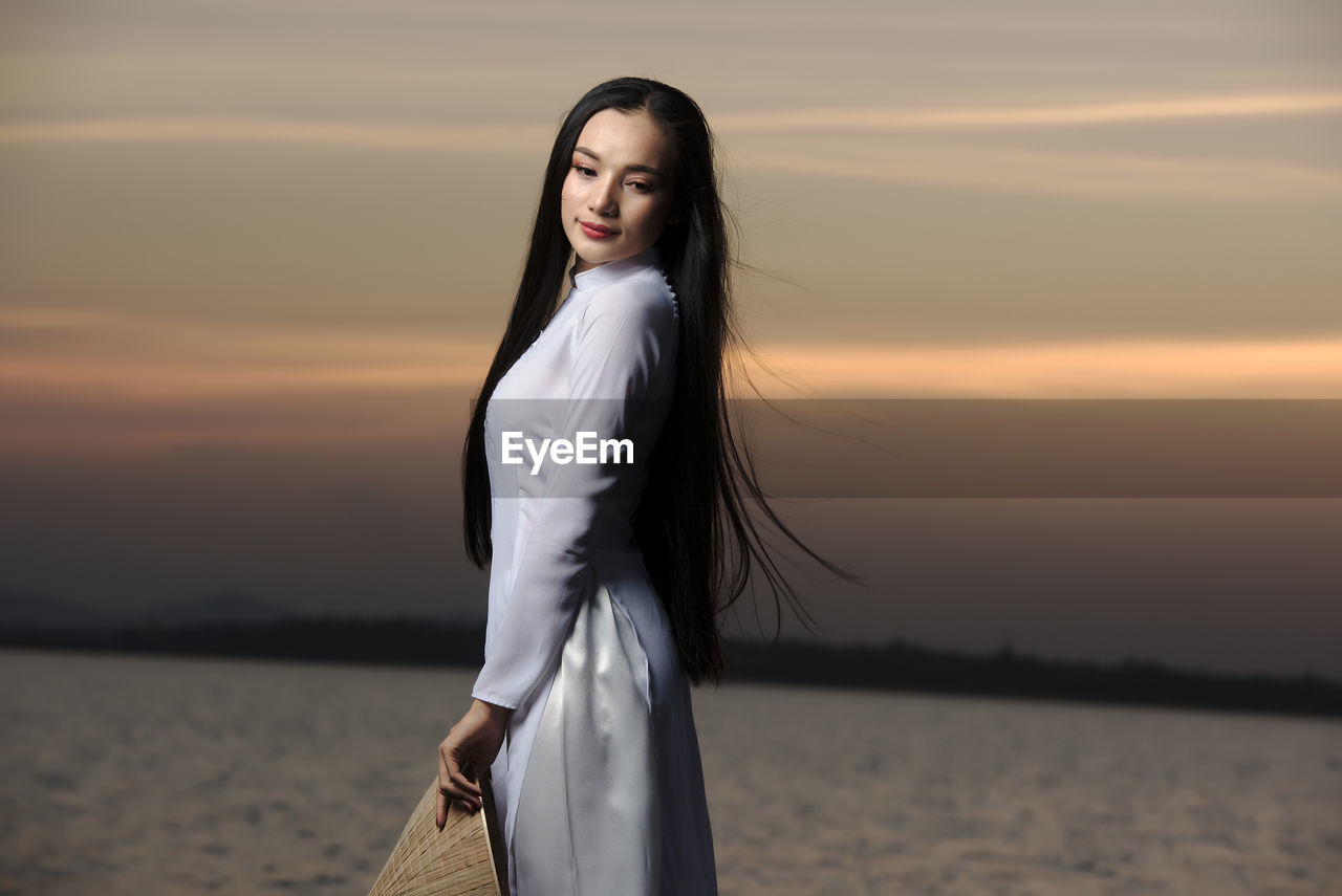 Portrait of beautiful asian girls with ao dai vietnam traditional dress on sunset landscapes.