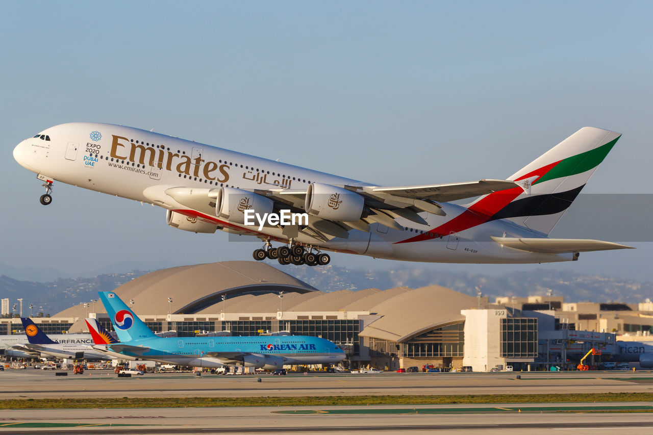 AIRPLANE FLYING OVER AIRPORT