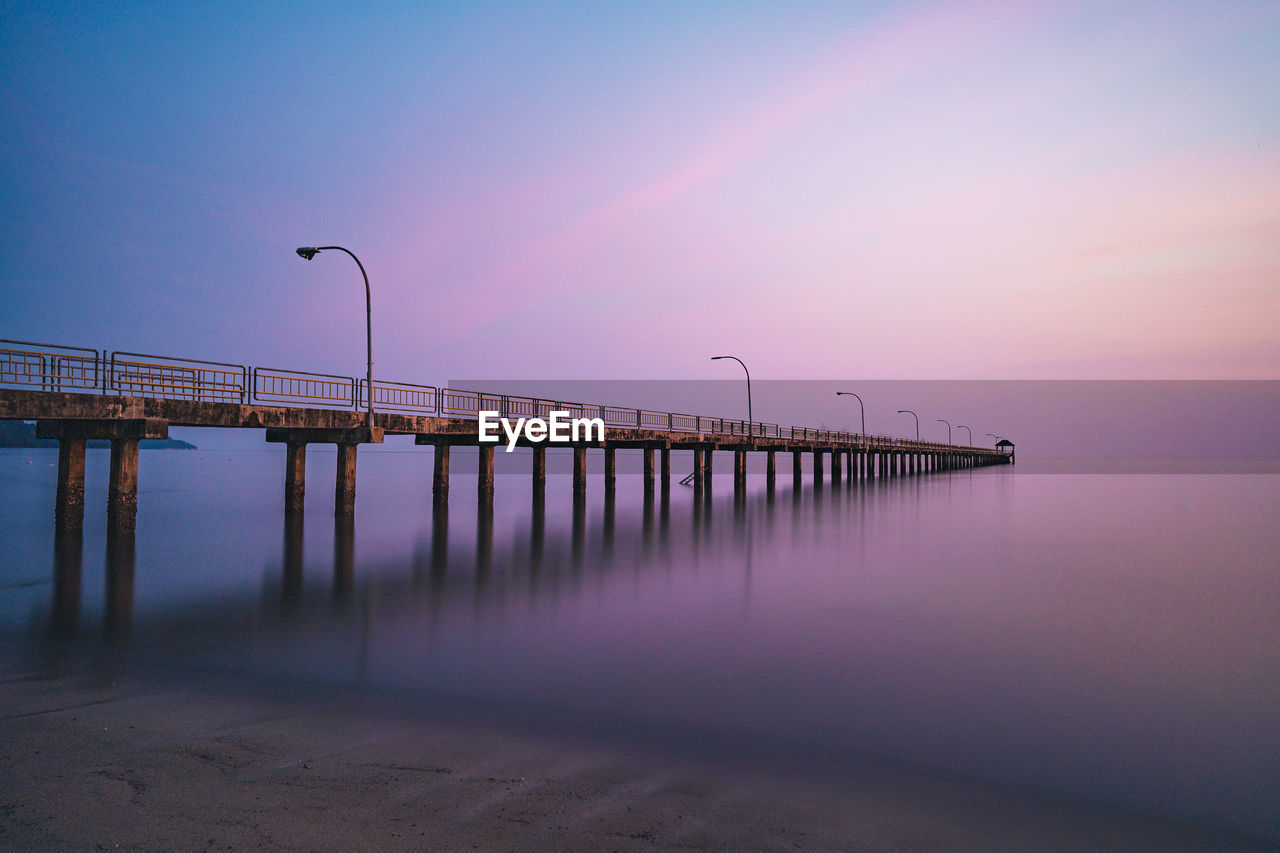 BRIDGE OVER SEA AGAINST SKY DURING SUNSET