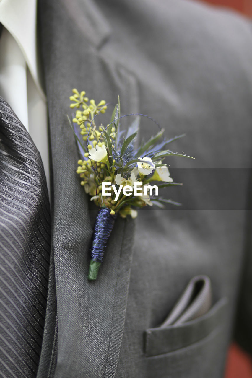 Midsection of bridegroom wearing flower bouquet on suit