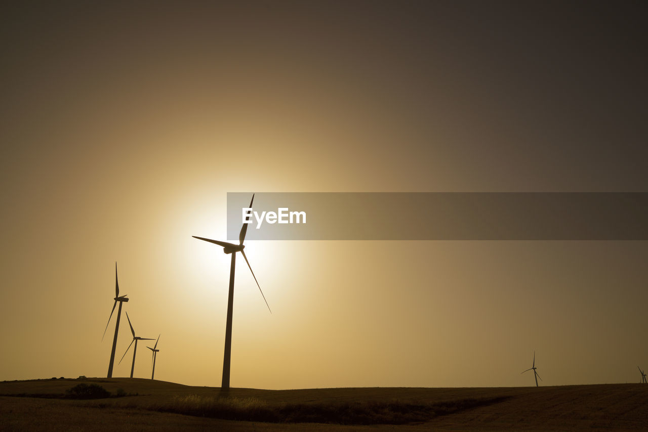Windmills for electric power production at sunrise.