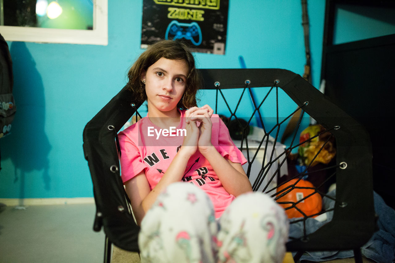 Teen girl clasps hands together while sitting in a bungee chair