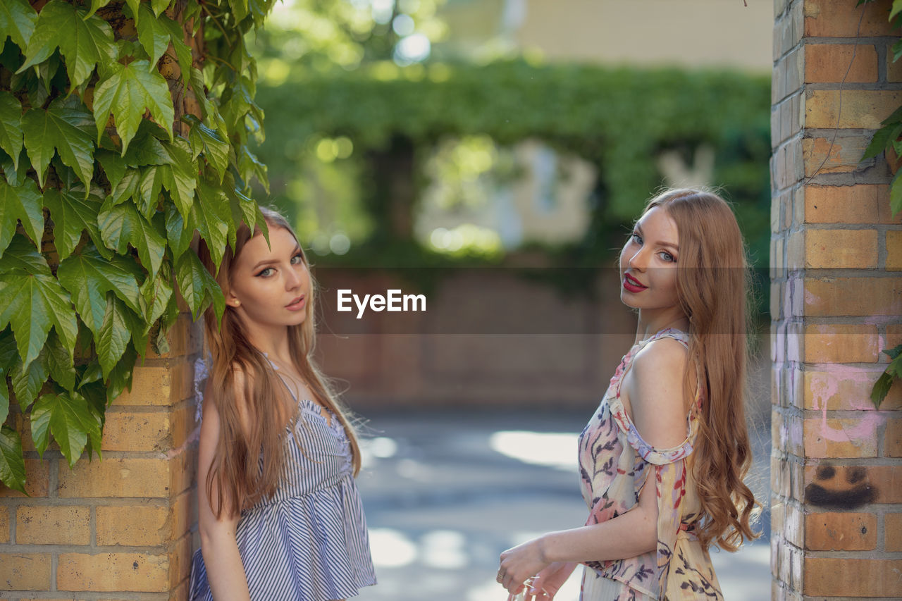 Portrait of beautiful friends standing at doorway in park