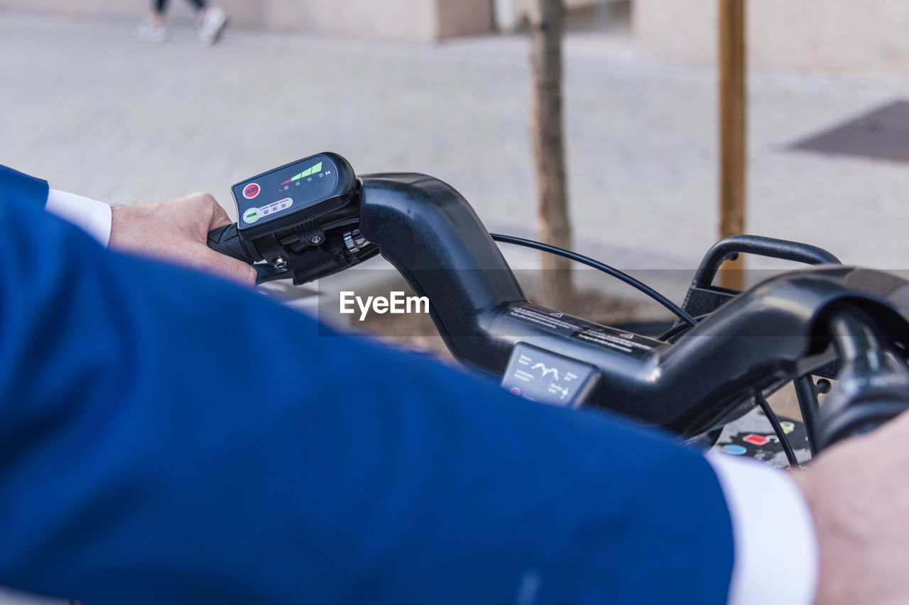 From above of crop anonymous male looking at lcd display with colorful symbols on electric bicycle