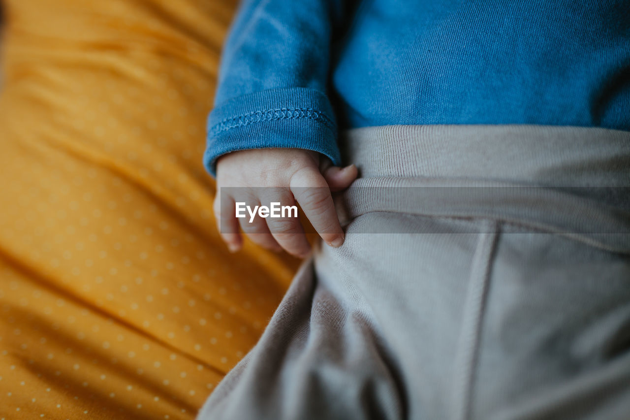 Midsection of newborn baby boy lying on bed at home