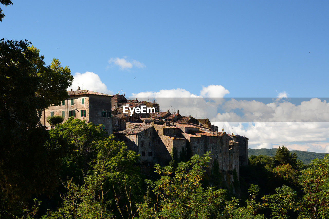 architecture, sky, built structure, building exterior, tree, building, nature, plant, history, travel destinations, the past, cloud, house, travel, castle, hill, no people, residential district, tourism, blue, land, landscape, ruins, rural area, outdoors, fort, city, environment, vacation, scenics - nature, ancient, old, château, village, medieval, day, home, beauty in nature
