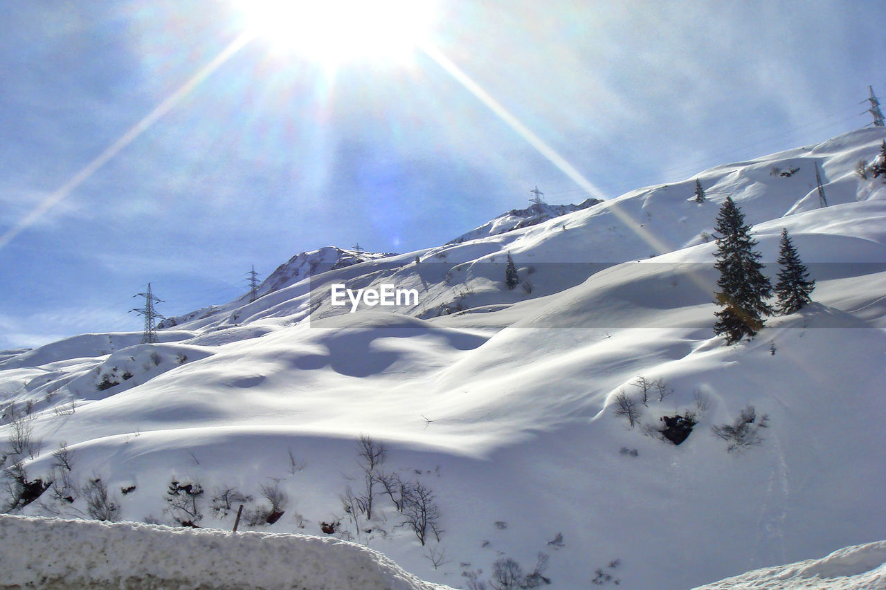 snow, cold temperature, winter, mountain, sunlight, sky, scenics - nature, lens flare, nature, sun, beauty in nature, environment, sunbeam, mountain range, landscape, skiing, snowcapped mountain, piste, winter sports, day, ski equipment, tranquility, sunny, tranquil scene, ski mountaineering, ski, travel destinations, travel, white, frozen, cloud, ski touring, non-urban scene, land, sports, outdoors, tree, mountain peak, holiday, forest, vacation, blue, back lit, idyllic