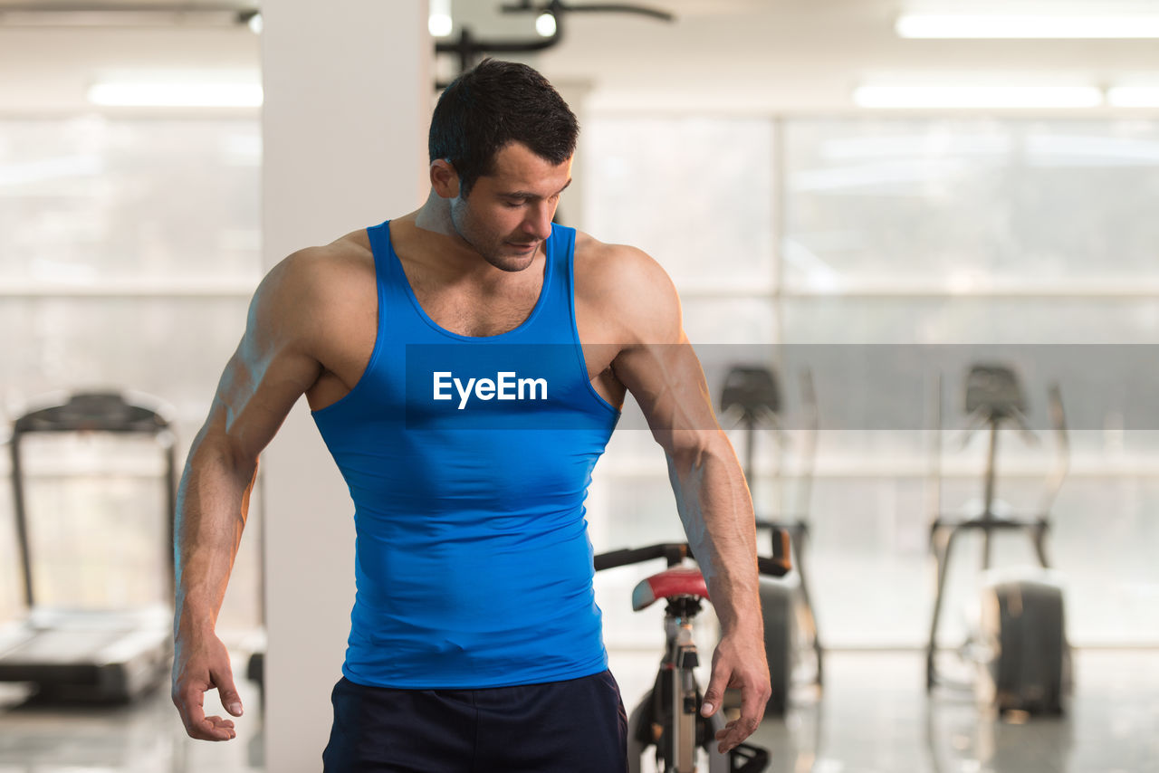 Muscular man wearing vest standing in gym