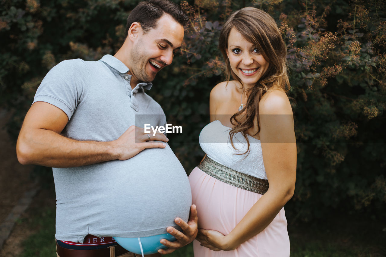 Pregnant woman making face while holding husband stomach