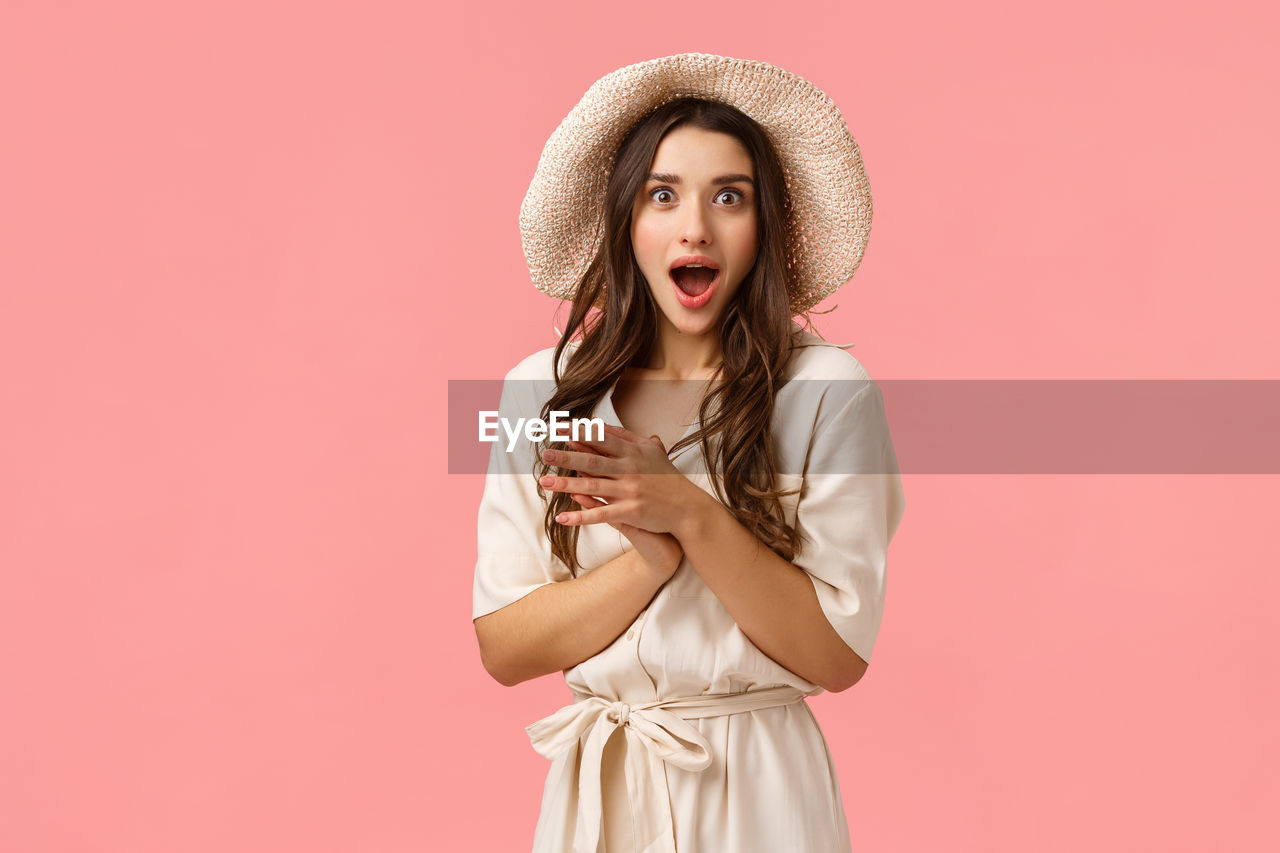 PORTRAIT OF A YOUNG WOMAN WEARING HAT AGAINST GRAY BACKGROUND