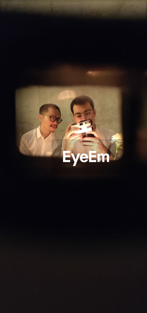 Man taking selfie in mirror reflection with friend