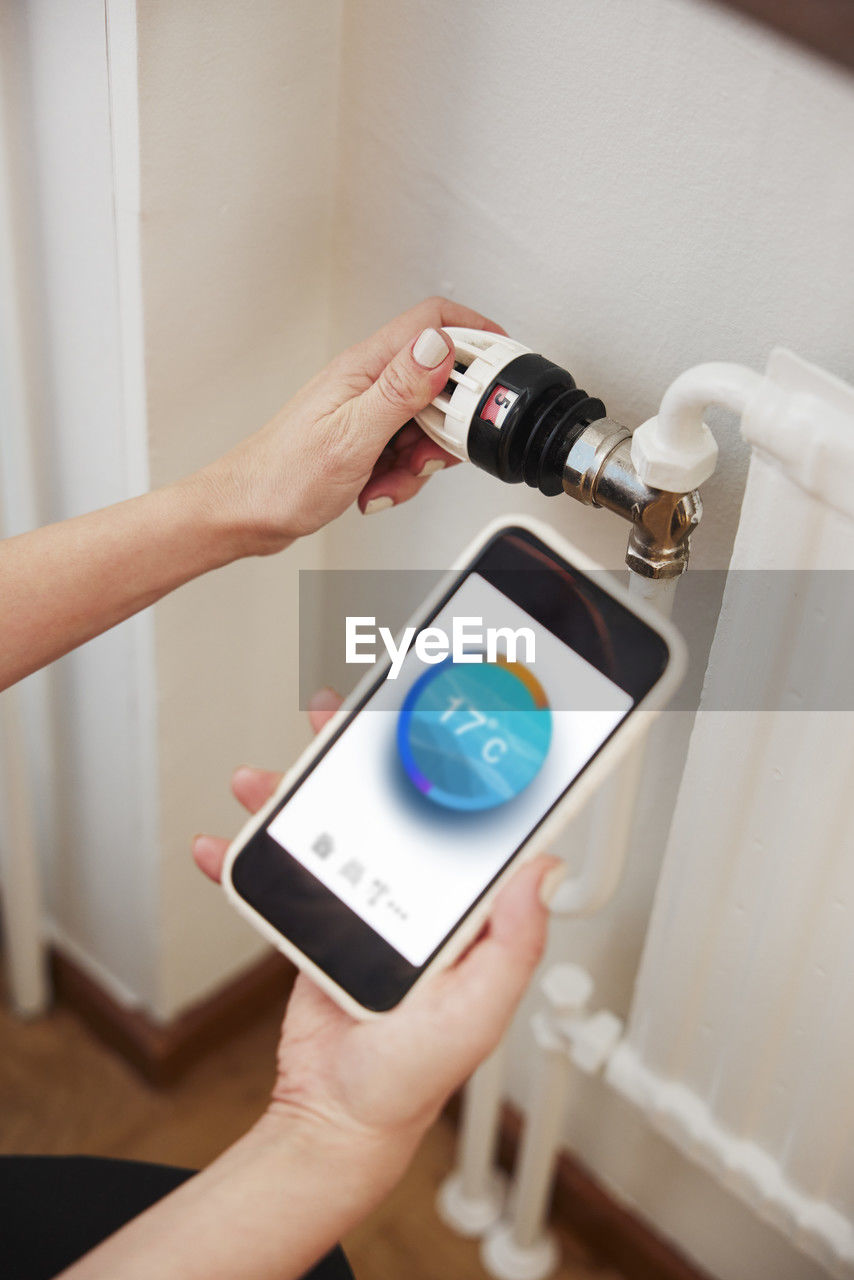 Woman using thermostat and app on phone