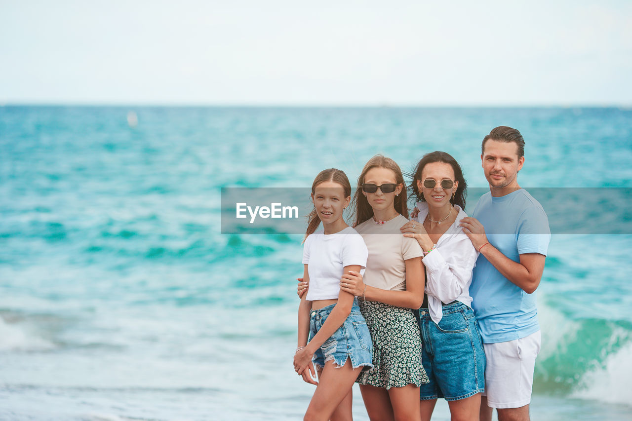 water, sea, vacation, women, group of people, beach, togetherness, happiness, emotion, holiday, adult, female, smiling, trip, land, summer, child, horizon over water, family, men, positive emotion, childhood, parent, sky, horizon, ocean, nature, leisure activity, shorts, cheerful, fun, bonding, copy space, clothing, travel, relaxation, enjoyment, ceremony, lifestyles, love, portrait, travel destinations, looking at camera, casual clothing, person, friendship, beauty in nature, standing, father, young adult, outdoors, day, shore, tourism, body of water, blue, carefree, three quarter length, small group of people, joy