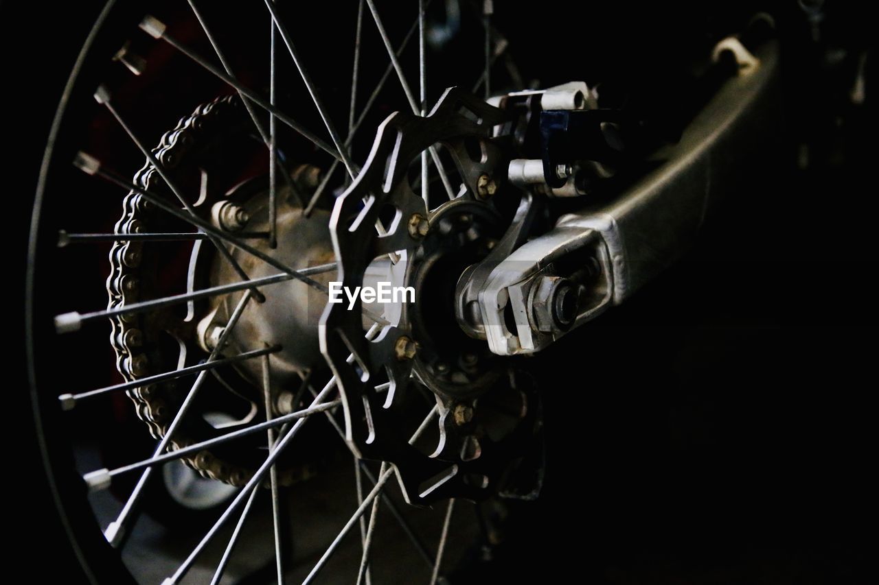 wheel, bicycle, vehicle, auto part, spoke, bicycle wheel, black background, close-up, indoors, transportation, metal, no people, mode of transportation, studio shot, sports equipment, gear, darkness, land vehicle, black, pedal