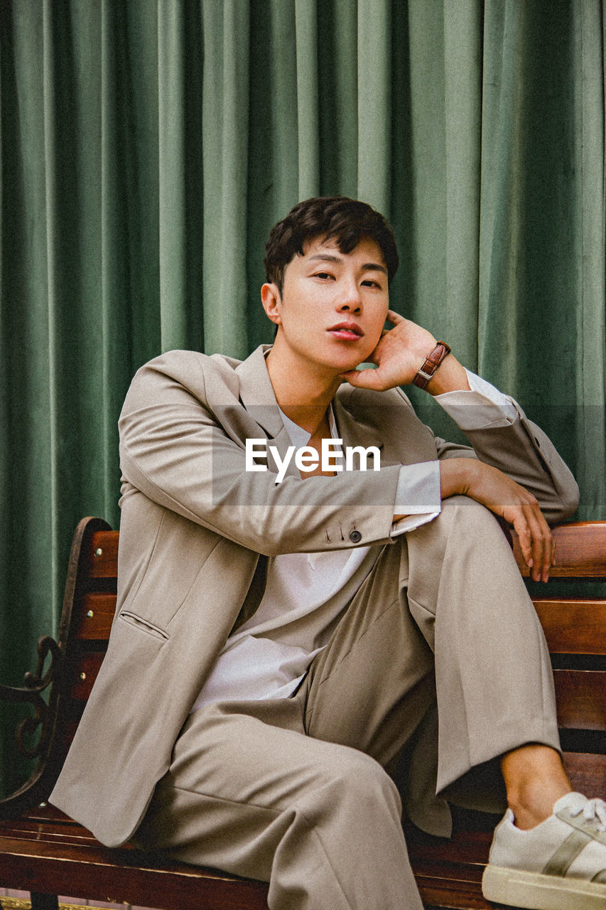 Portrait of handsome young man sitting on bench