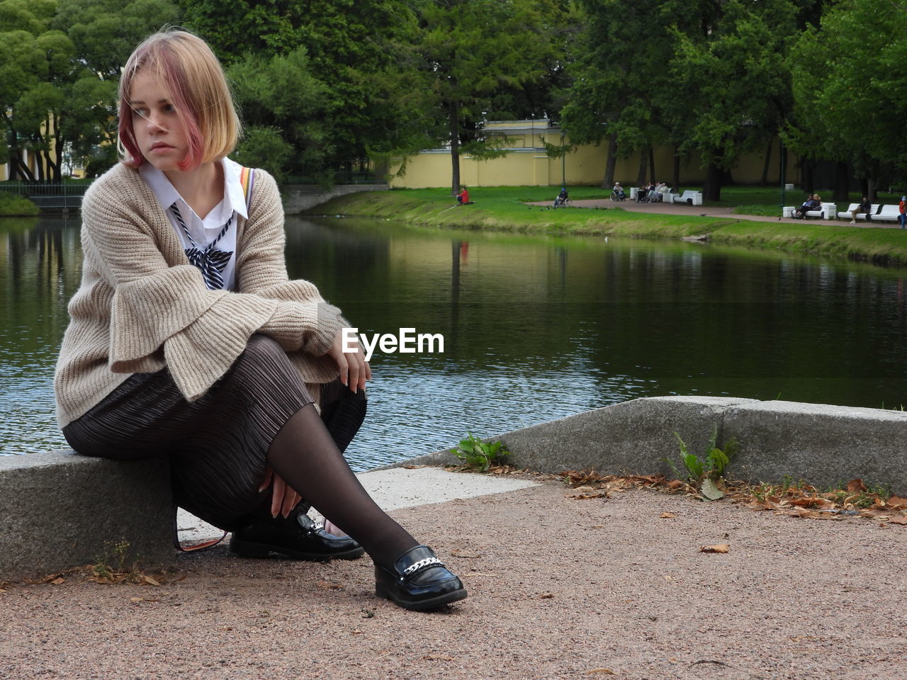 Girl sitting by lake in park