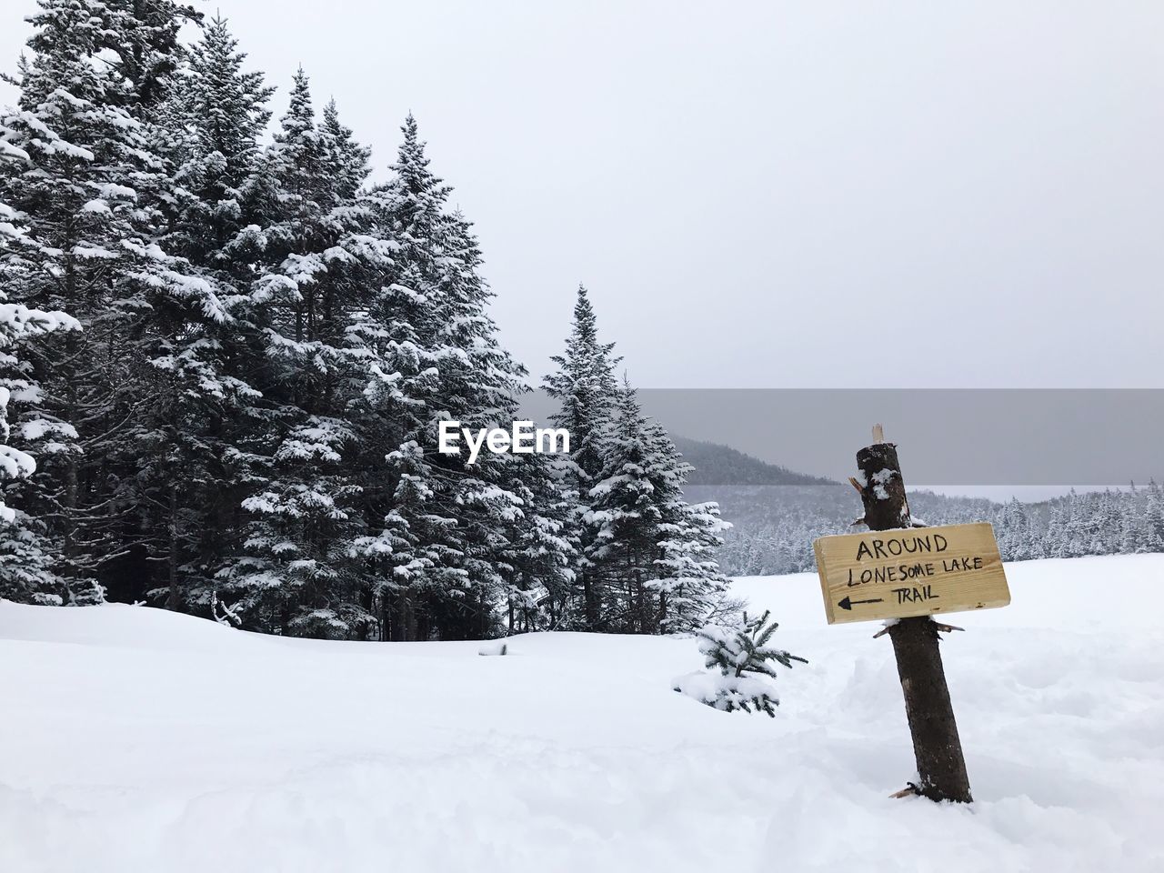 Information sign on snow covered landscape against sky