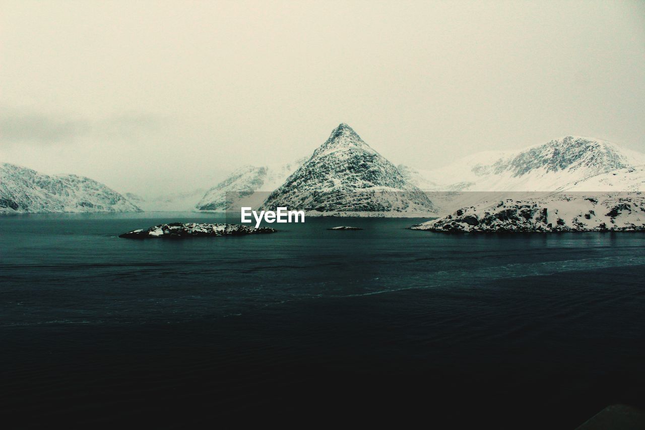 Scenic view of sea and snowcapped mountains against sky