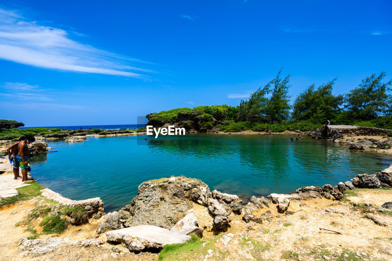 Scenic view of rocks by sea against blue sky