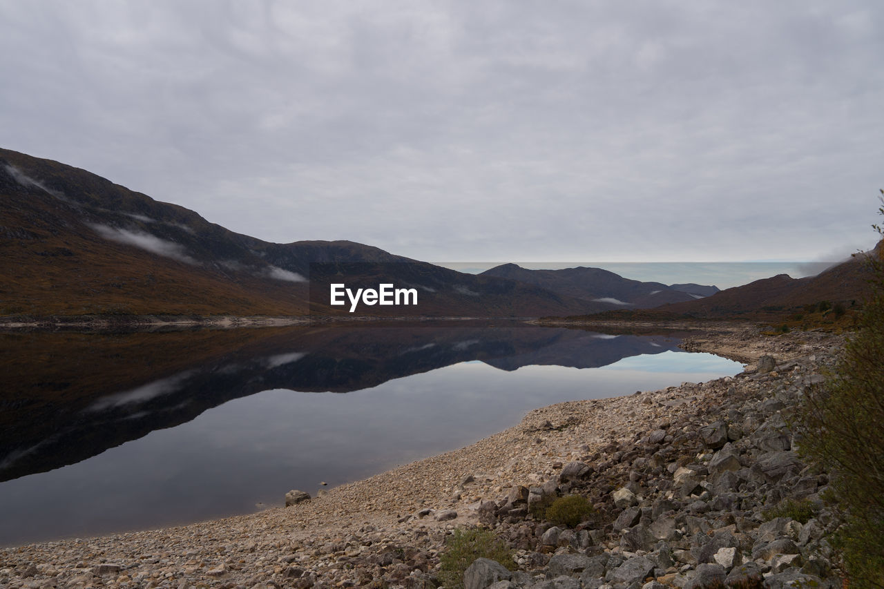 SCENIC VIEW OF LAKE BY MOUNTAIN AGAINST SKY