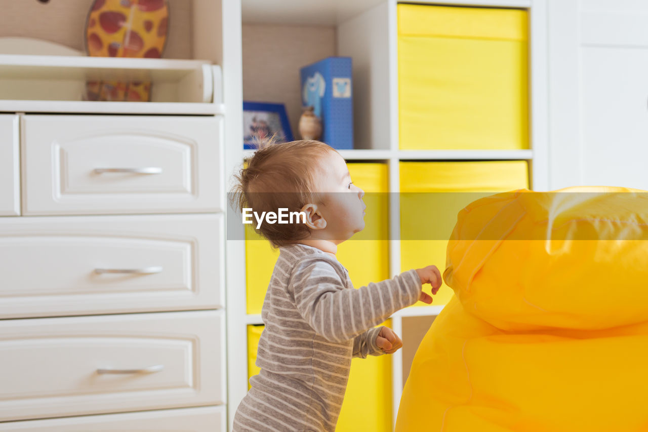 Side view of boy looking at camera at home