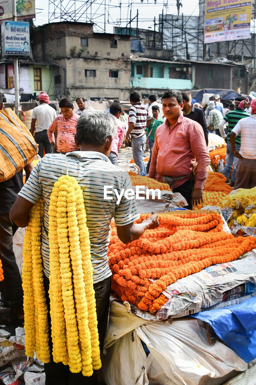 REAR VIEW OF PEOPLE AT MARKET