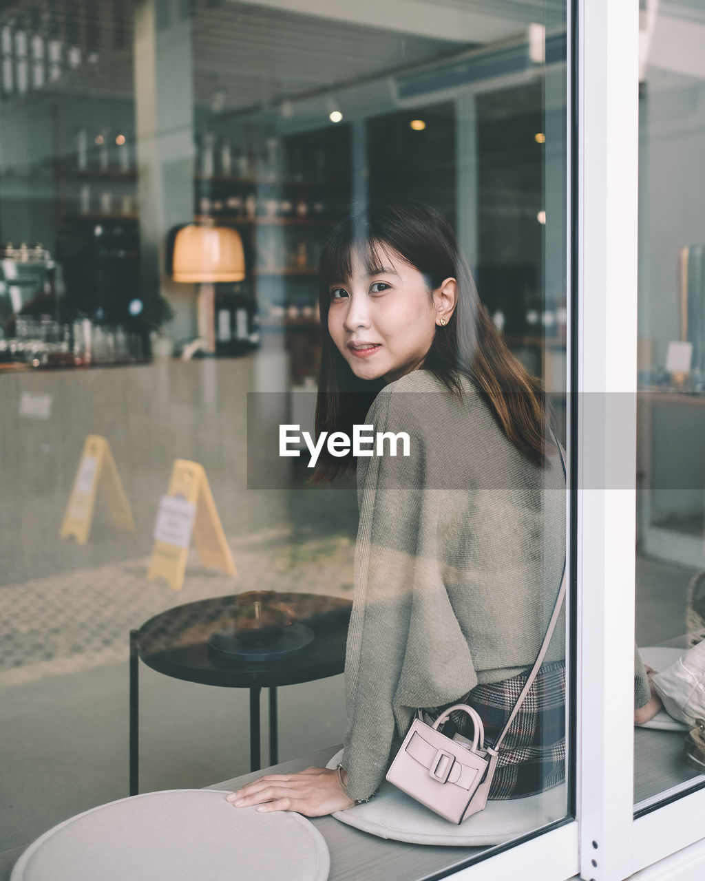 Portrait of smiling young woman looking through restaurant window