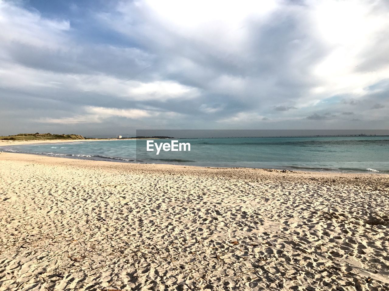 SCENIC VIEW OF BEACH AGAINST CLOUDY SKY