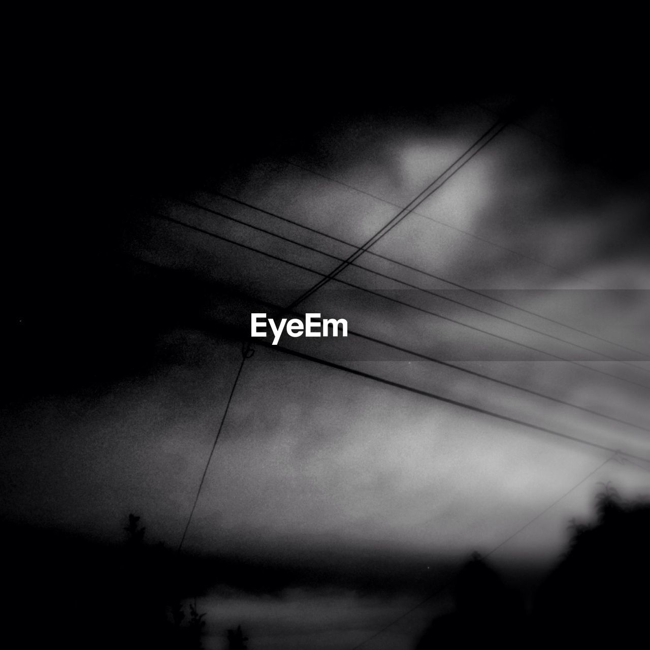 Low angle view of power lines against cloudy sky at dusk