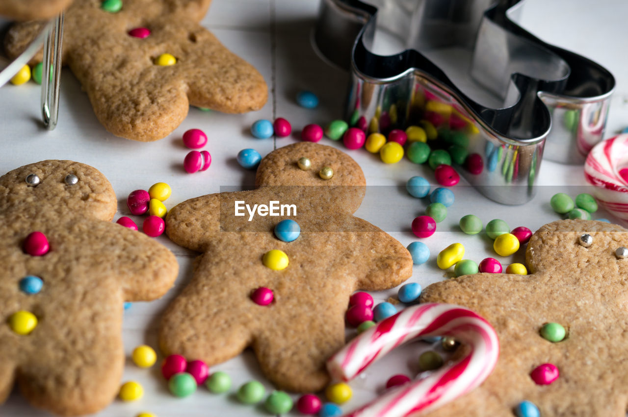 Close-up of gingerbread cookies with cutter and candy cane on table