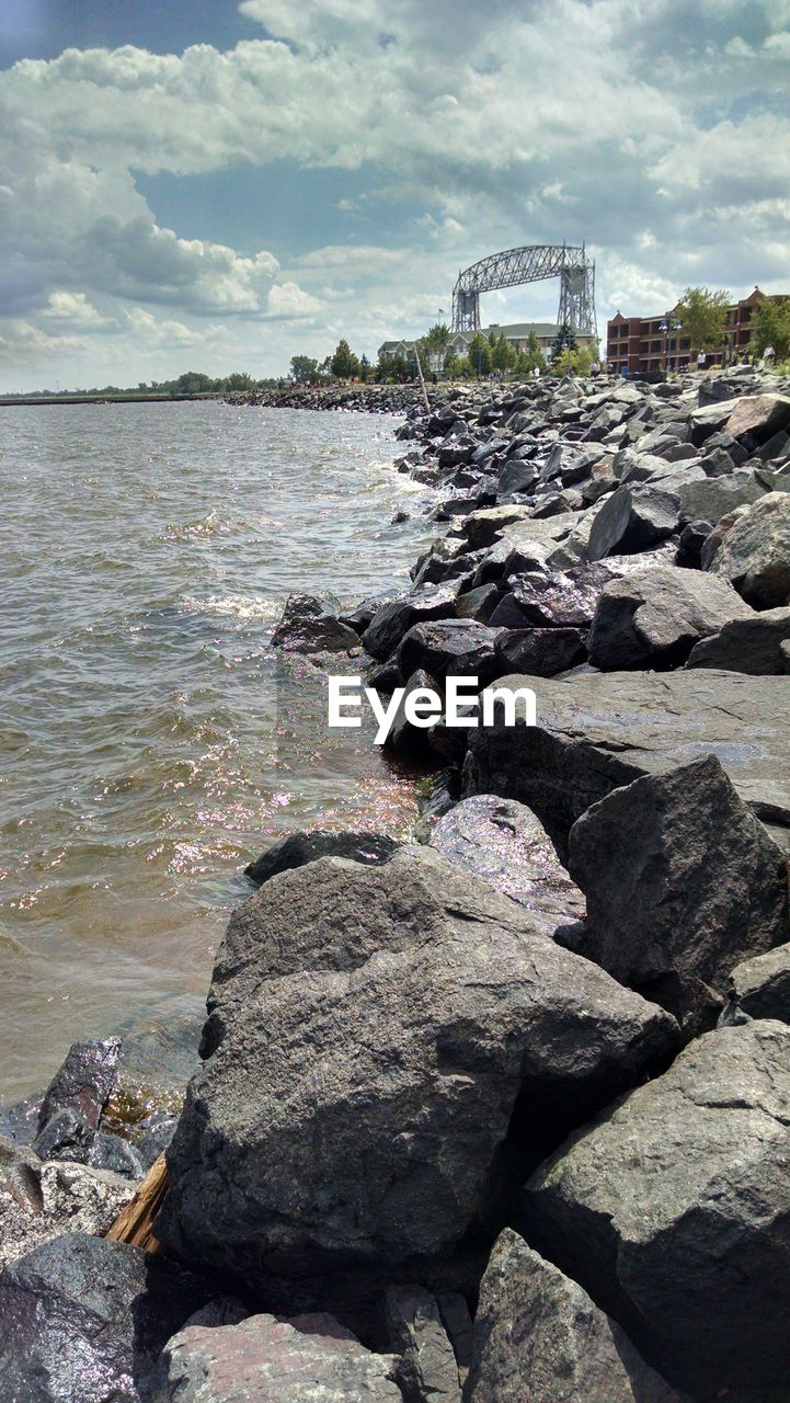 View of rocks in sea against cloudy sky