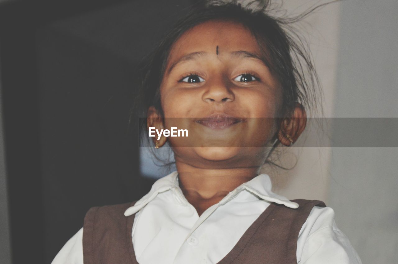 Portrait of smiling girl standing against wall