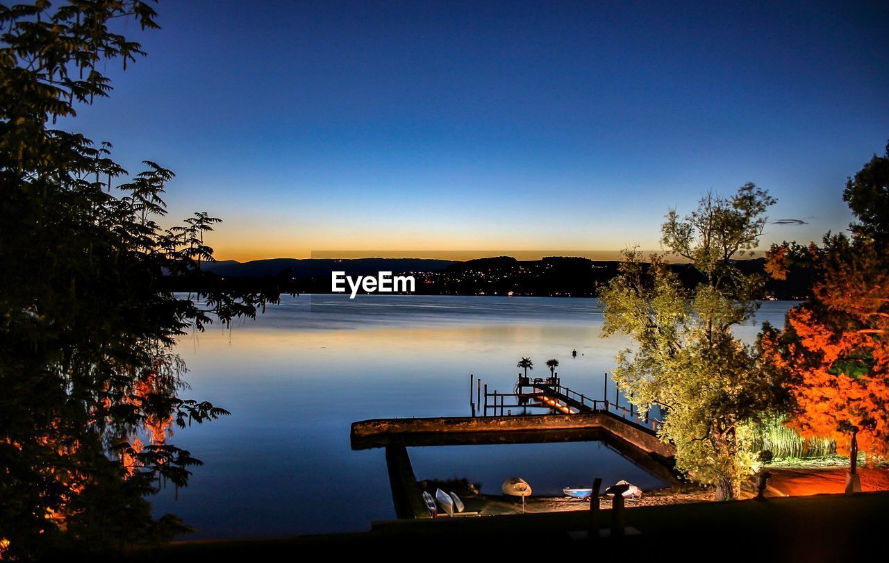 HIGH ANGLE VIEW OF LAKE AGAINST CLEAR BLUE SKY AT DUSK