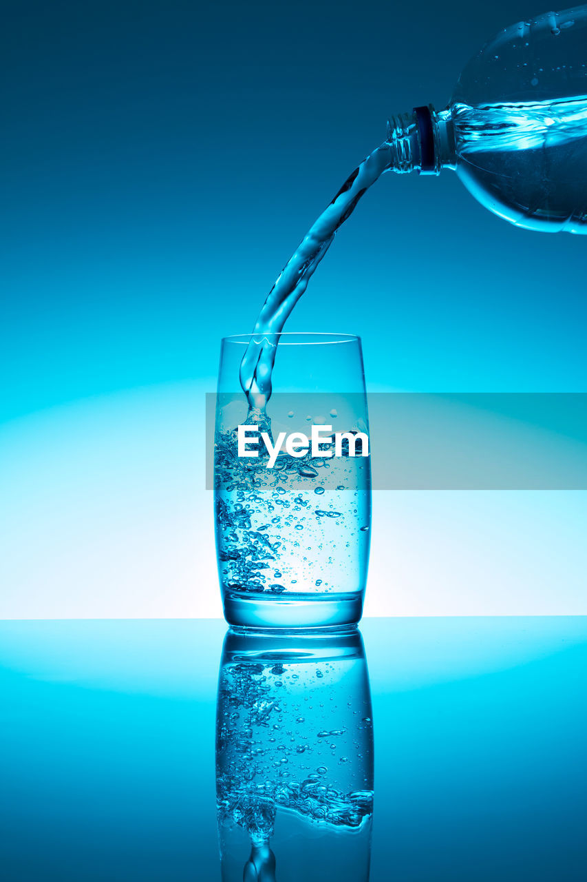 CLOSE-UP OF DRINK GLASS AGAINST BLUE WATER