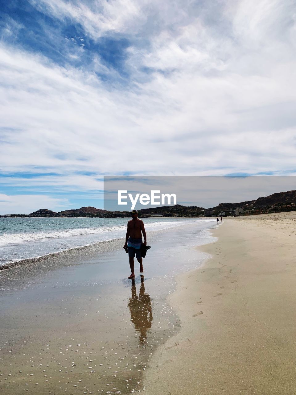 REAR VIEW OF BOY STANDING ON BEACH