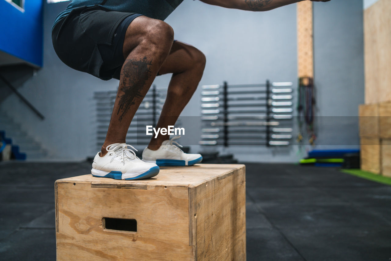 Low section of man standing on box in gym