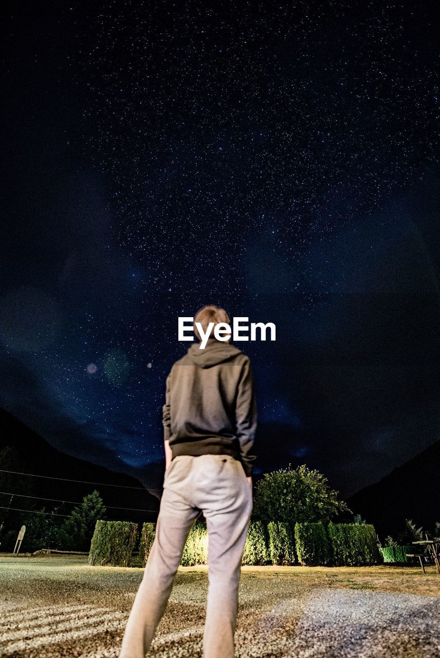 Low angle view of man standing against sky at night